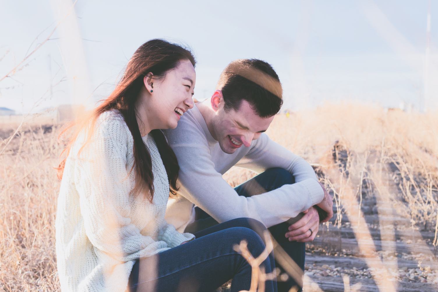 Couple Sitting and Laughing on a Railroad Tracks