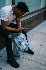 Man Holding his iPhone Wearing Black Ripped Knee Jeans