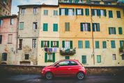 Red Fiat 500 Parks in front of Old Yellow Buildings with Green Shutters in Siena Italy