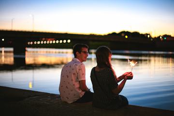 Couple of Young People Sitting on the Dock Against a Blurred Background
