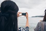 Woman Holding the White iPhone, Taking Photo of Small Island
