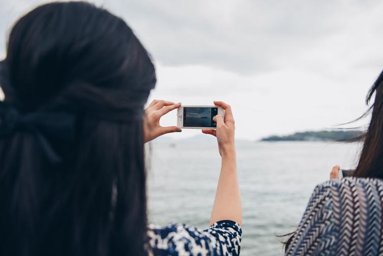 Woman Holding the White iPhone, Taking Photo of Small Island