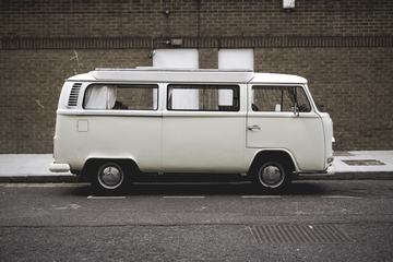 A White Volkswagen Minibus Parked in Front of Brick Wall