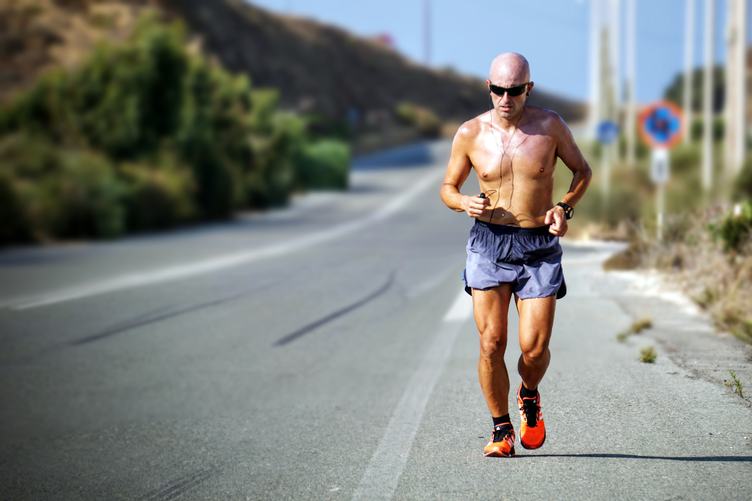 Bald Tanned Man with Sunglasses Jogging During a Hot Day
