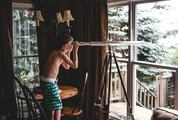 A Young Boy Observing the Nature Through a Telescope from Indoors