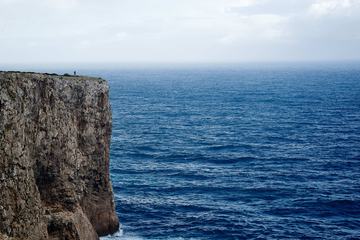 Solitary Person Standing at the Top of a Cliff