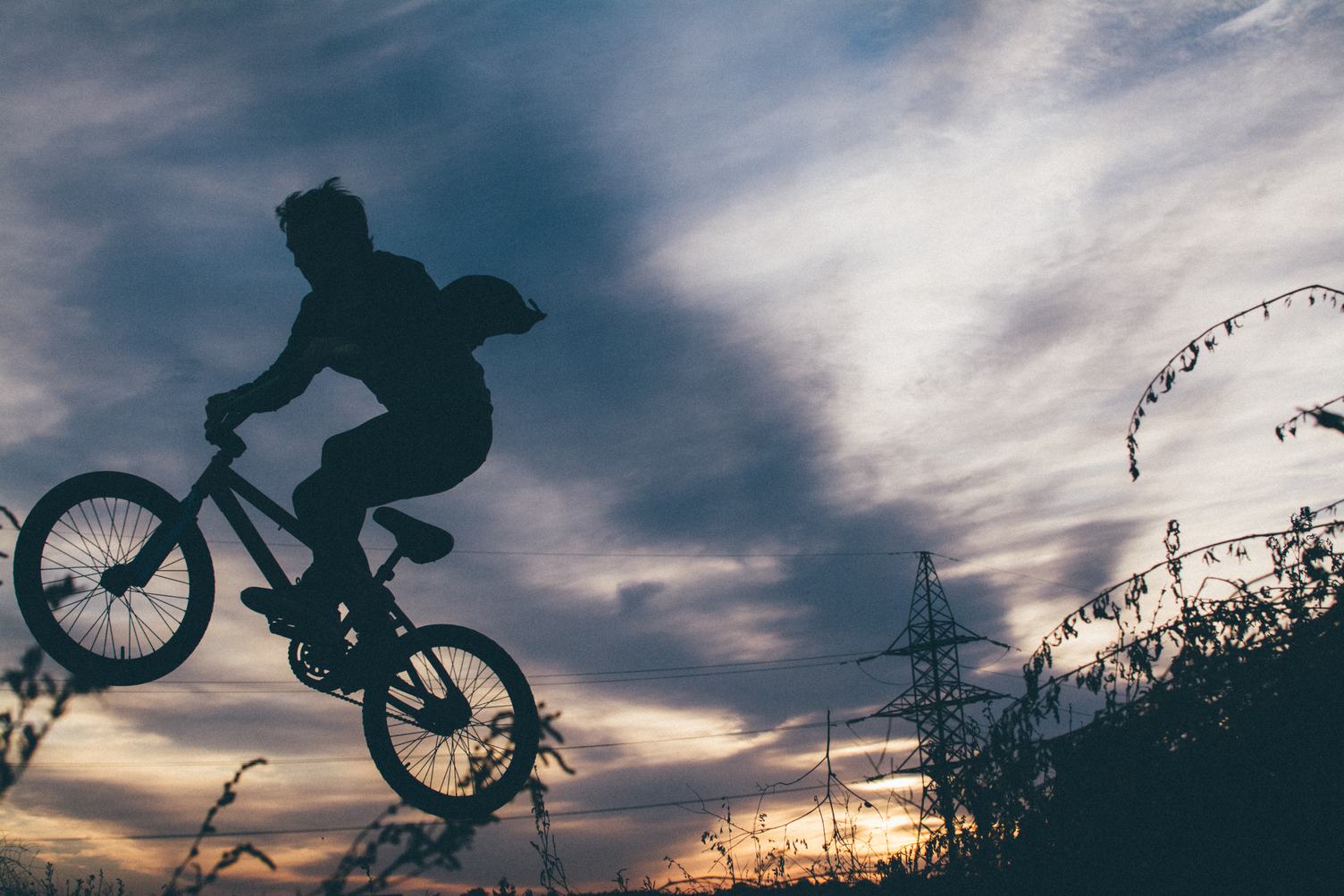 Silhouette of a Young Man Jumping on a Bike