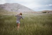 Young Girl Wearing Striped Shirt Walking Through A Green Meadow