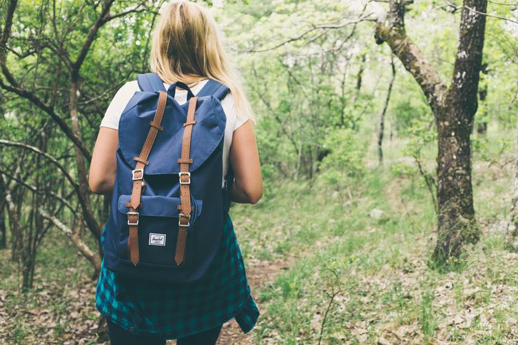 Blond Girl with a Backpack Exploring a Forest