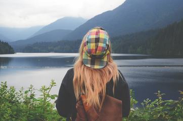 Girl with a Backpack Looking at a Mountain Lake