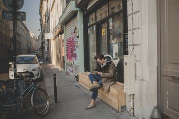 Sitting Man with his Smartphone in a Small Street