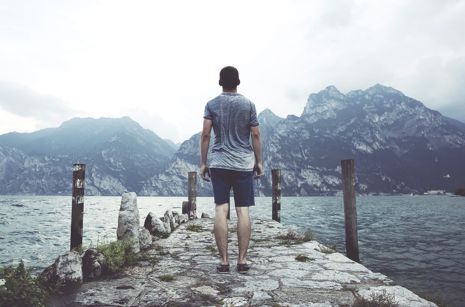 Young Man on a Stone Pier in front of a Mountain Lake