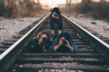 Three Young Girls Taking Pictures on Railroad Tracks