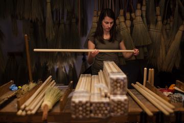 Young Woman Assembling Wooden Brooms