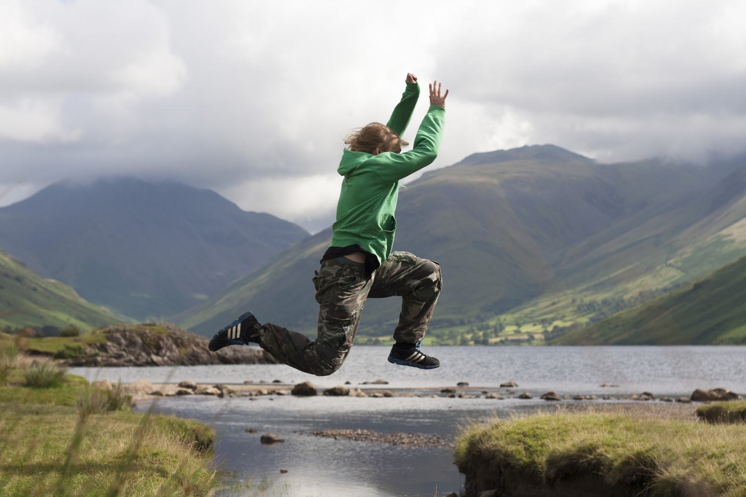 Young Boy Jumping Over the Mountains Lake Water