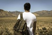 Young Man Alone with a Travel Backpack in a Desert