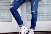 Woman Posing in Ripped Jeans against White Door