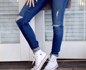 Woman Posing in Ripped Jeans against White Door
