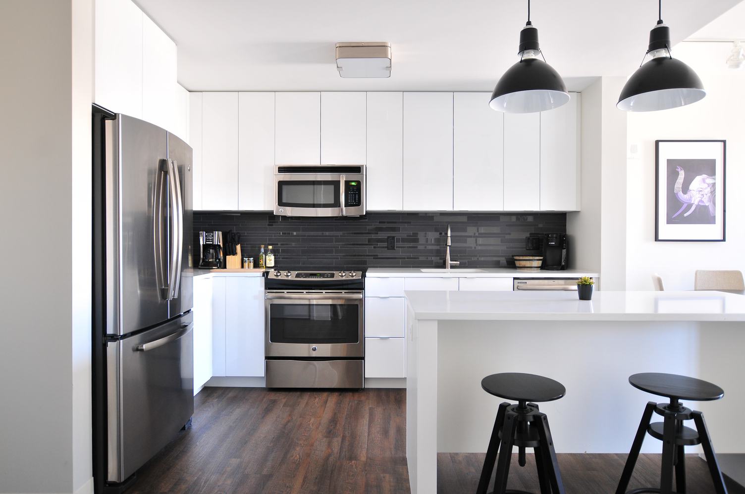 White Open Kitchen with Island, Fitted Cabinets and Black Stools