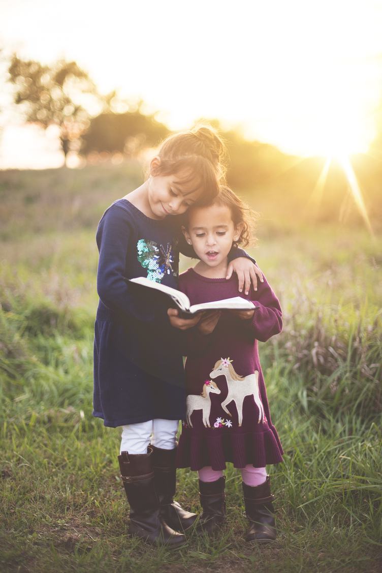 Happy Sisters Hugging with Love and Reading Book Together