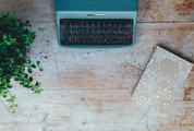 Blue Vintage Typewriter with Plant and Notebook on the Grung Wooden Table