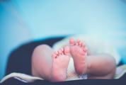Soft Newborn Baby Feet against a Blue Blurred Background