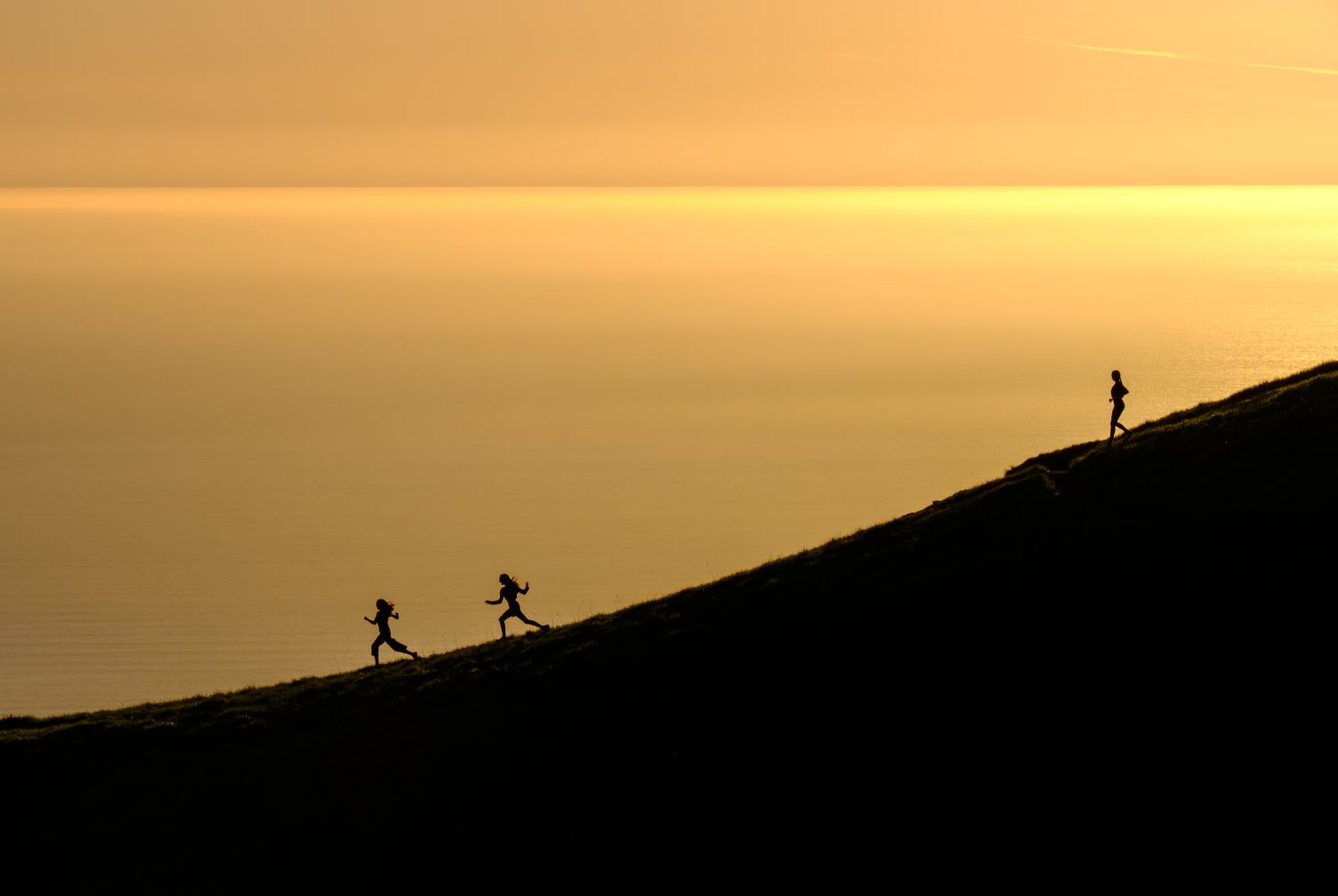 Women Silhouettes Running at Sunset with the Ocean in the Background