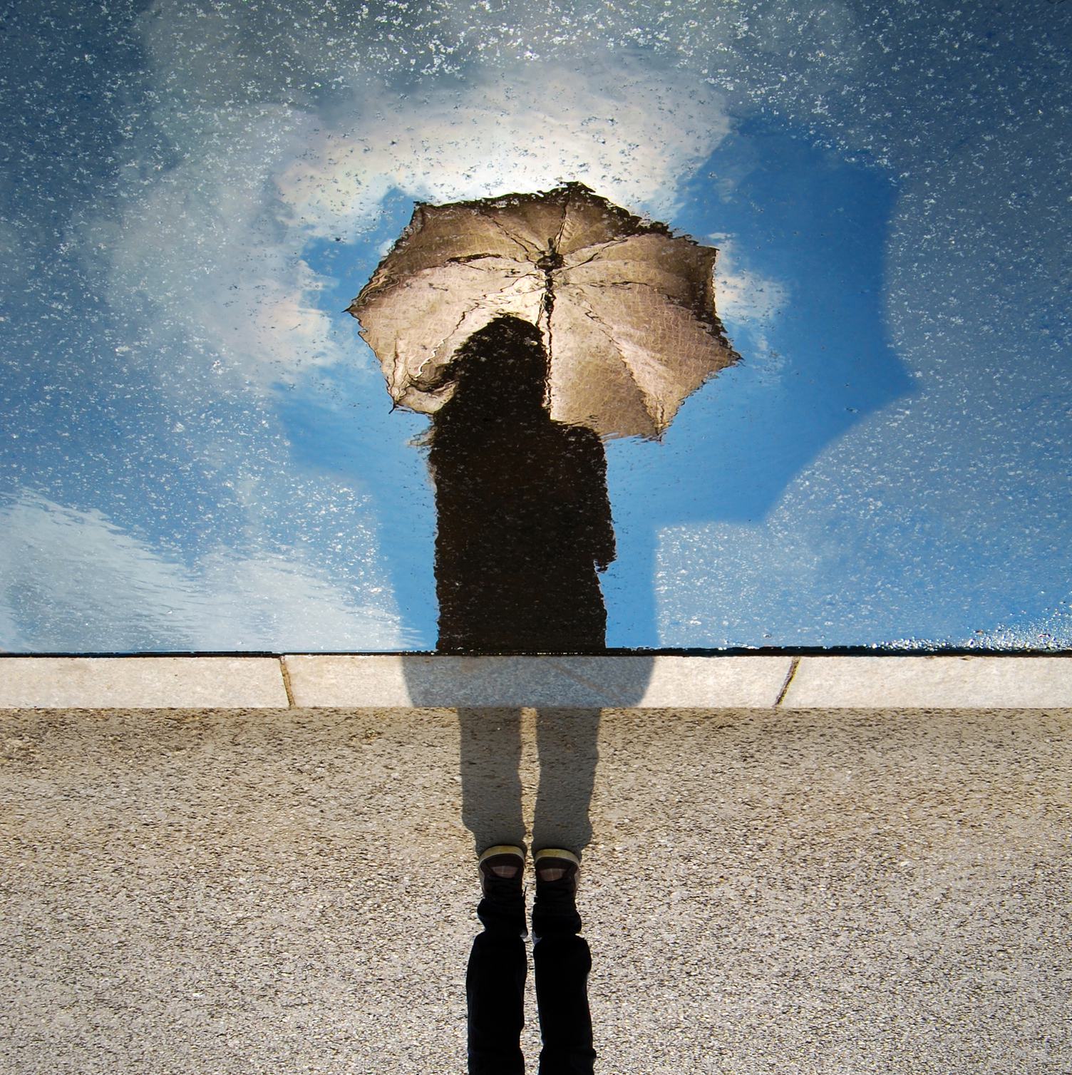 Puddle Reflection Silhouette of Girl with Umbrella against Blue Sky