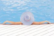 Young Woman Wearing Striped Hat Enjoying a Swimming Pool