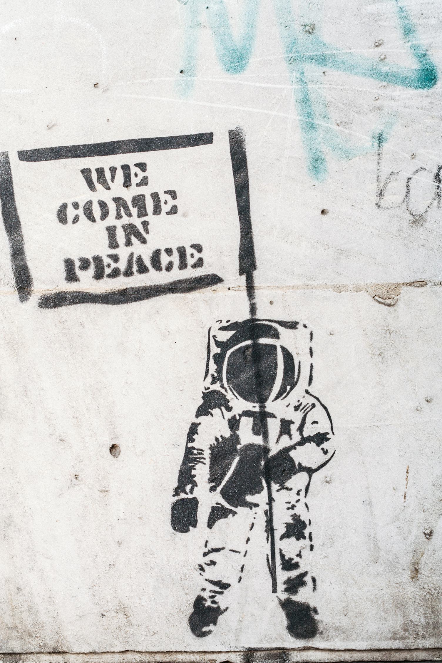 Dirty Wall with Graffiti Astronaut Holding Flag "We Came in Peace"