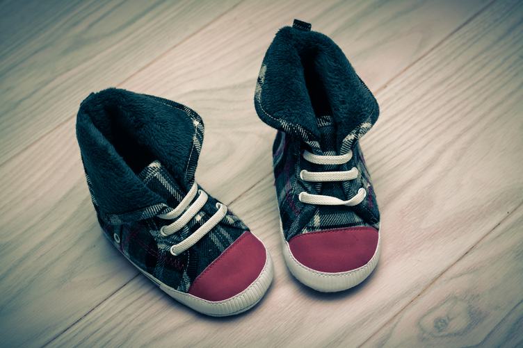 Pair of Cute Baby Sneakers over White Wooden Floor