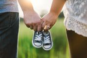 Future Parents Holding Hands and a Pair of Little Baby Shoes