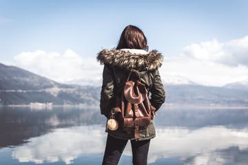 Young Woman with Backpack Looking on the Lake, Rear View