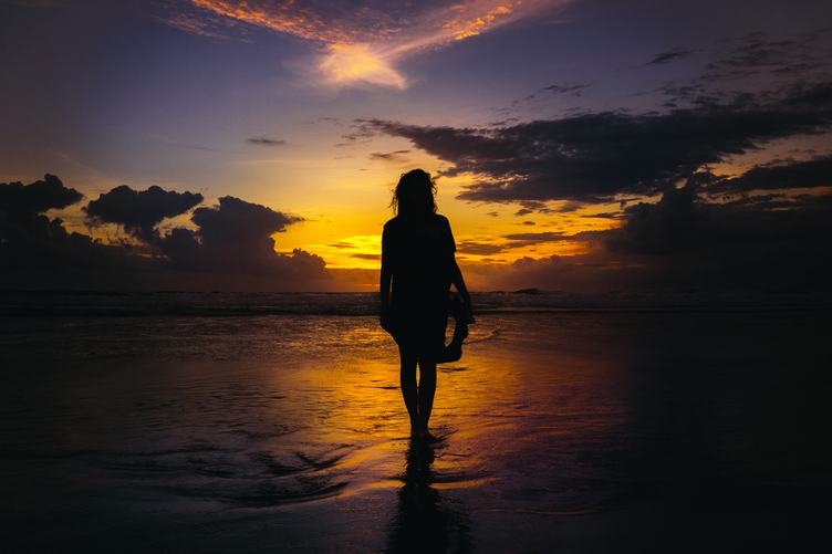 Woman Walking on the Beach at Sunset