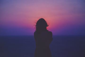 Young Woman Standing against Pink and Purple Sky