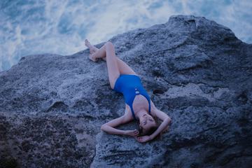 Beautiful Woman in Blue Swimsuit Lying on Rock