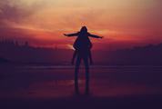 Man Carrying Girl Piggyback at Sunset
