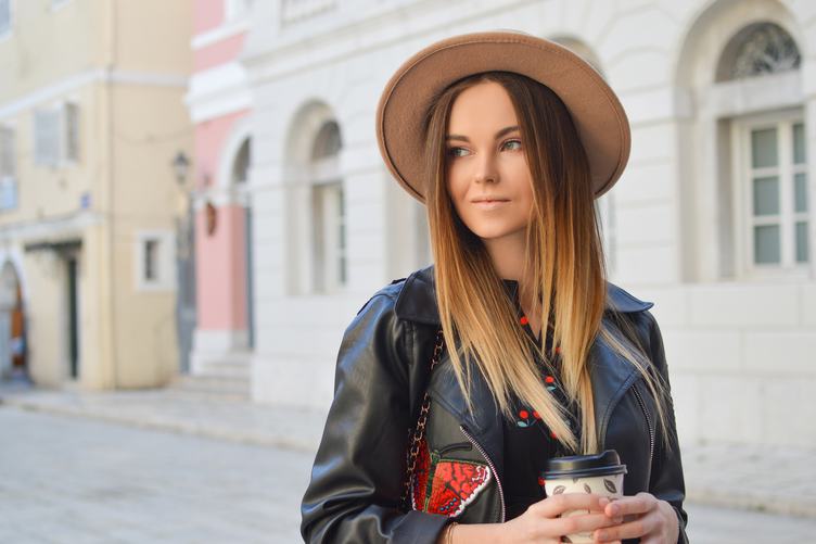 Beautiful Fashionable Woman in a Hat and Black Leather Jacket Holding Coffee