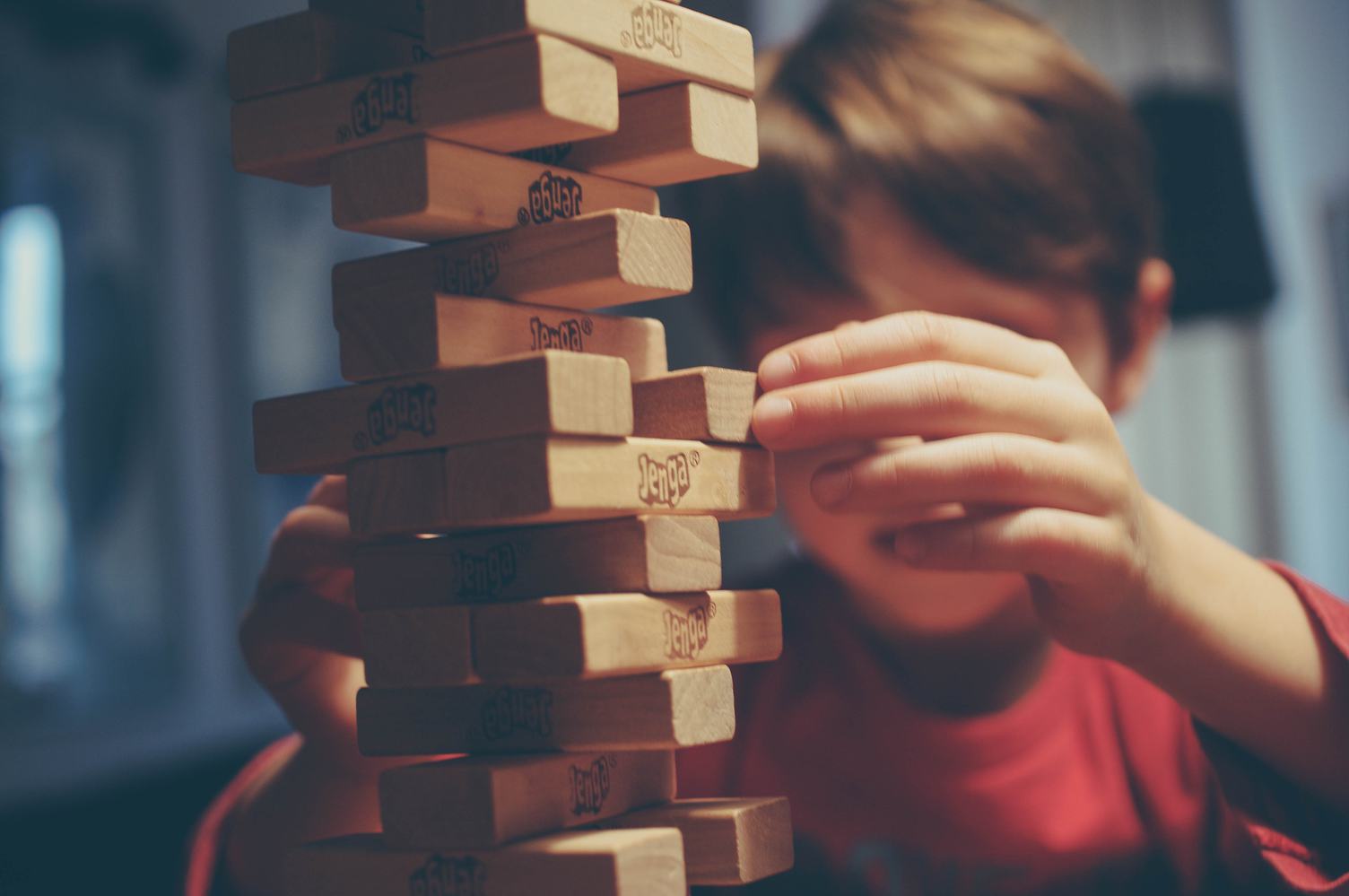 Boy is Playing Jenga, a Wood Blocks Tower Game