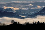 Silhouette of Trees and Building in the Valley in Foggy Mountains