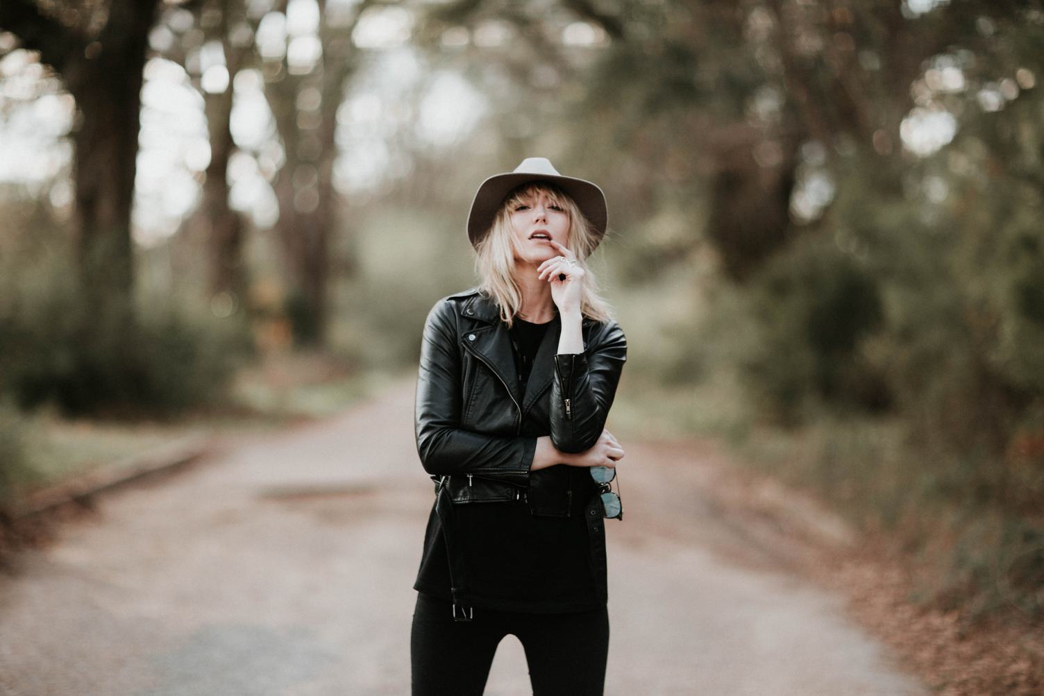 Fashion Blonde Woman Posing Outdoor in Black Hat and Leather Jacket