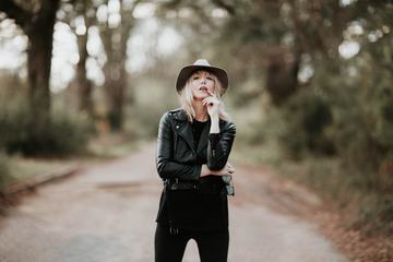 Fashion Blonde Woman Posing Outdoor in Black Hat and Leather Jacket