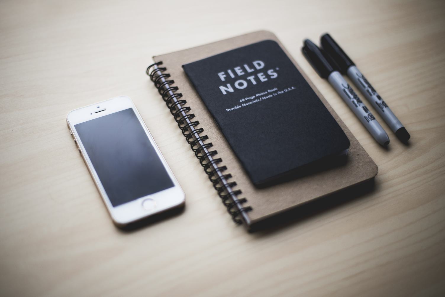 Notepad, iPhone and Pen on Wooden Background