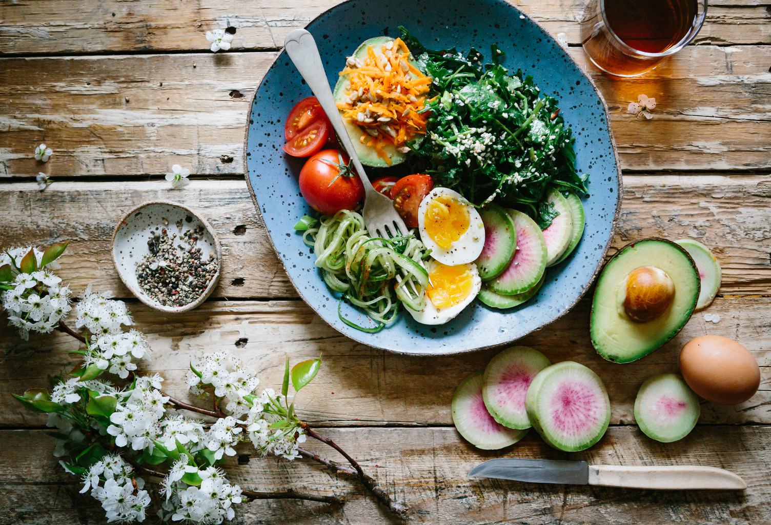 Top View of Healthy Salad Bowl with Eggs, Tomatoes, Avocado and other Vegetables on Wooden Table