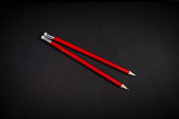 Two Red Pencils on Black Background