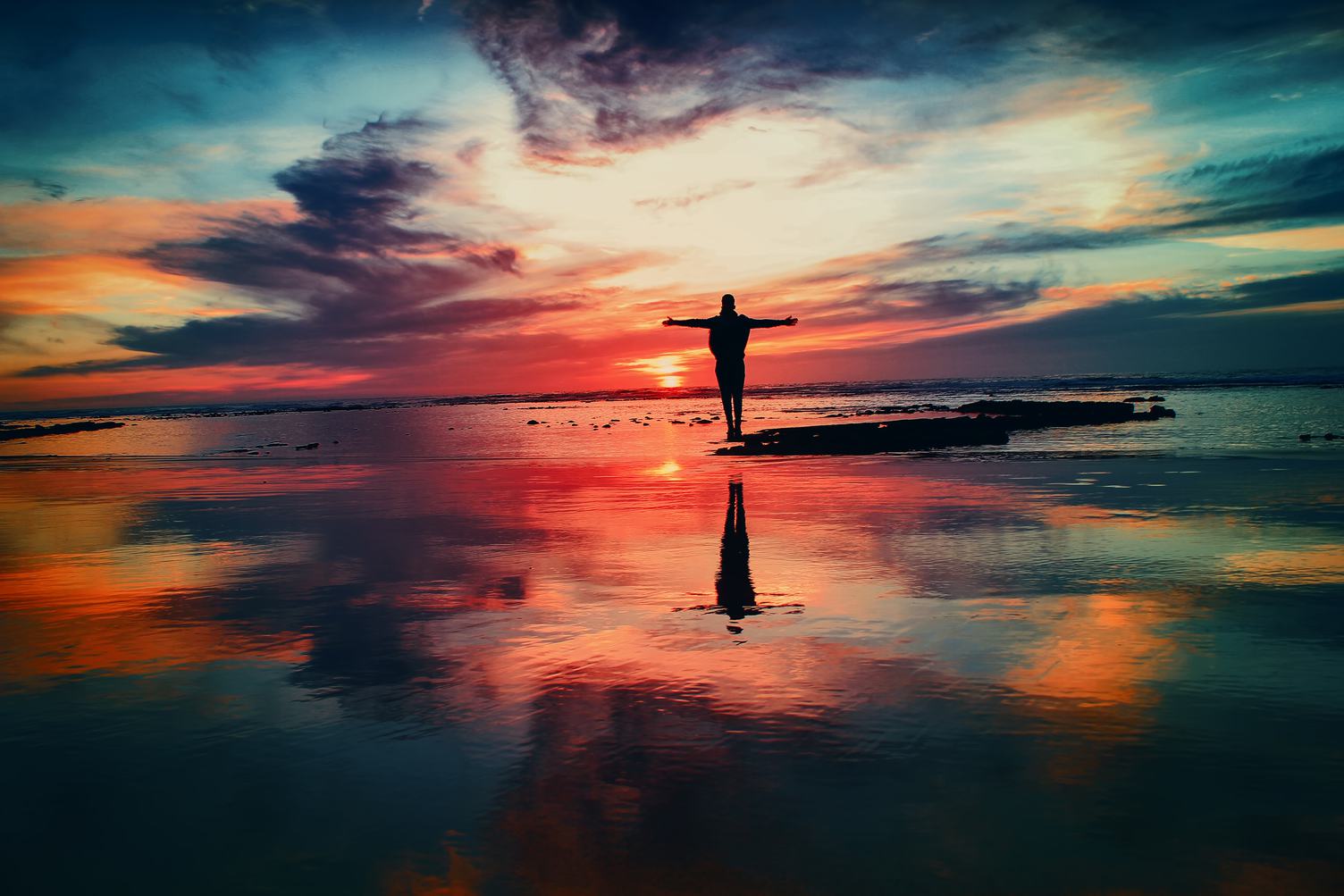 Men with Open Arms Standing in Water Against the Incredible Sunset Sky