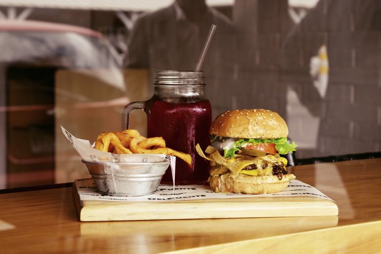 Tasty Burger with Fries and Beverage on Wooden Table