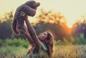 Girl Holding Teddy Bear on the Field at Sunset