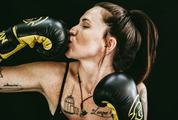 Woman Kissing her Boxing Gloves over Black Background