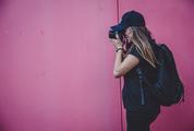 Female Photographer Shooting on a Pink Wall Background
